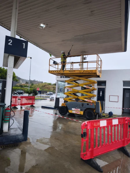 pintores pintando área de servicio y gasolinera subido en un elevador