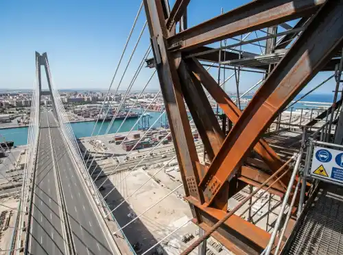 Andamios y vigas listos para pintar estructuras metálicas de gran envergadura en un puente atirantado industrial.